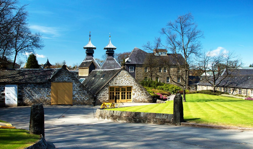 Stone building with conical roofs and manicured lawn under a clear blue sky.