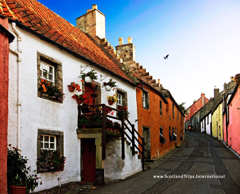 Charming colorful houses on a narrow street, with flowers and a blue sky.