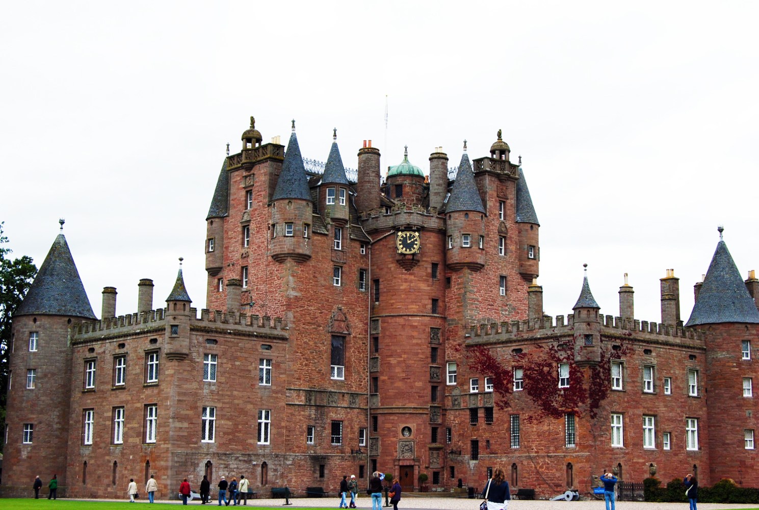 Majestic Gothic castle with multiple towers and a clock in cloudy weather.