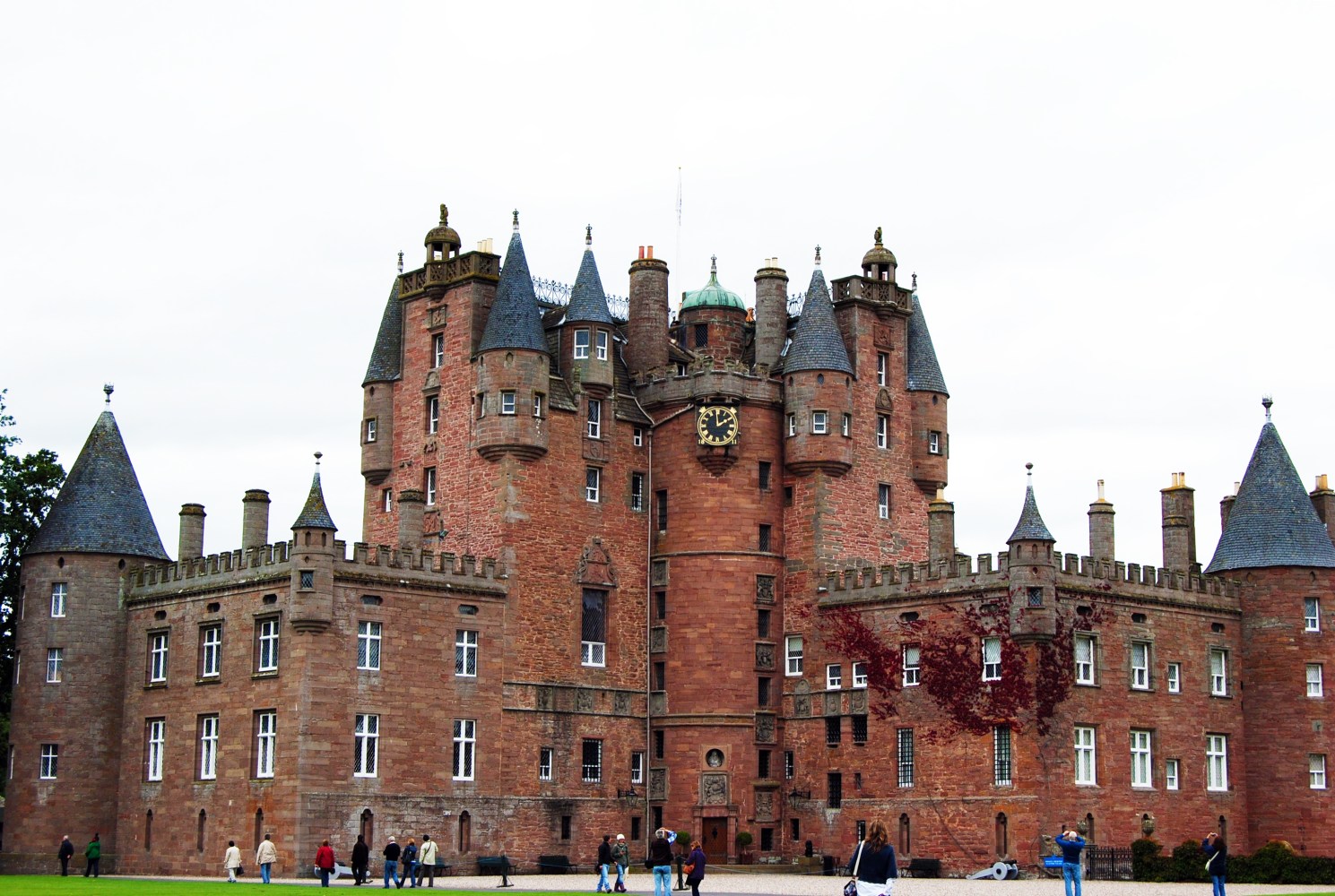Large medieval castle with tall towers and a clock in front.