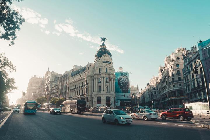 Urban street scene with cars and historic buildings under a clear sky.